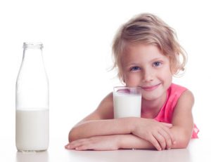 Girl drinks milk from glass on white background